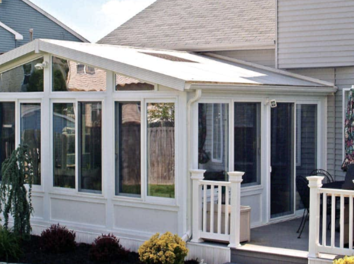 White four-season sunroom suite addition with a gable glass roof built onto a home