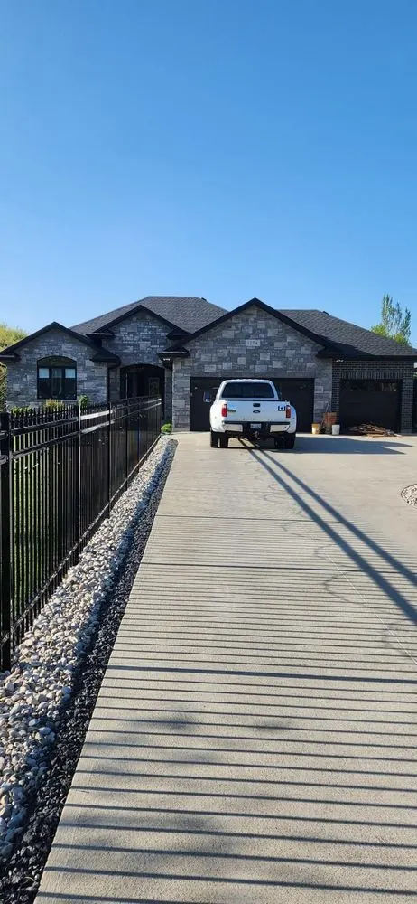 Aluminum driveway gate and fence leading to a detached garage