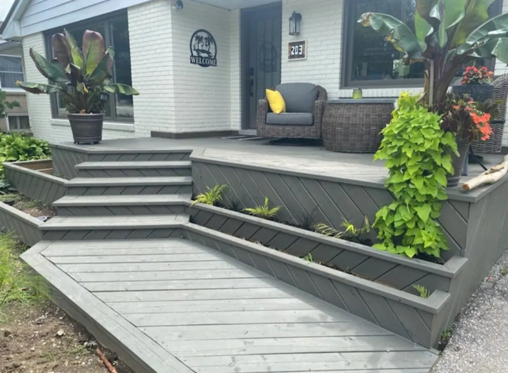 Grey composite front porch deck with wide mitred steps and built-in planter boxes in Sarnia